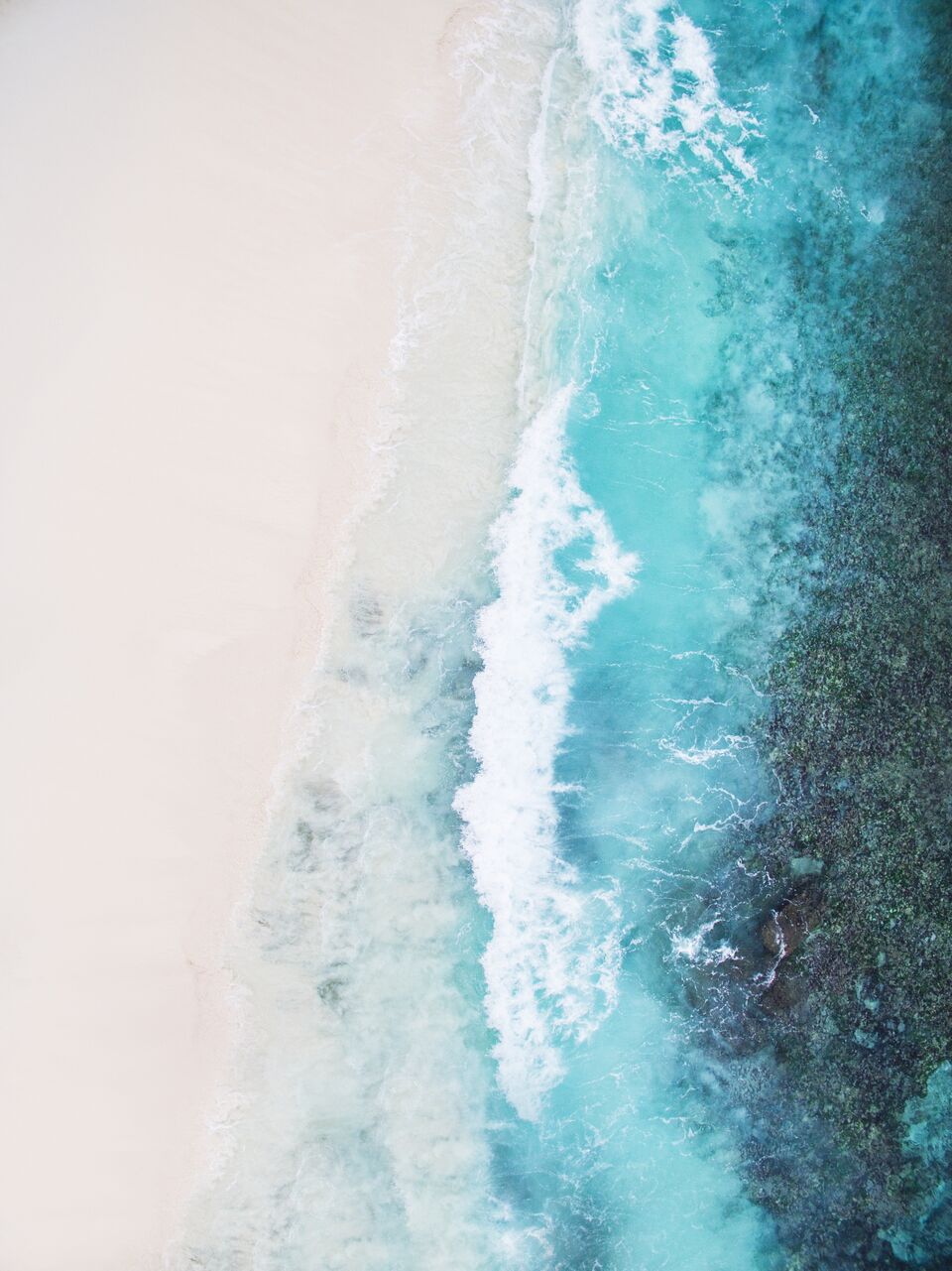 Beautiful tropical white empty beach and sea waves seen from above. Seychelles Grand Anse beach aerial view