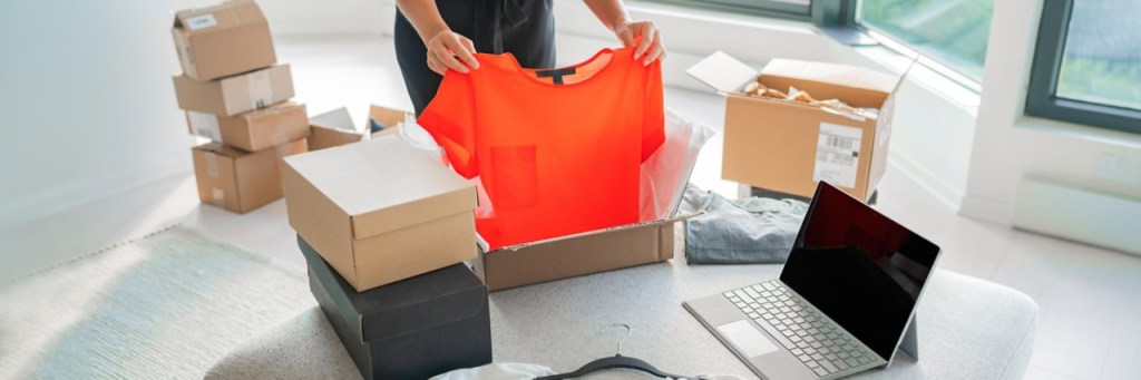 Woman packing new clothing fashion purchase in shipping packages for delivery.