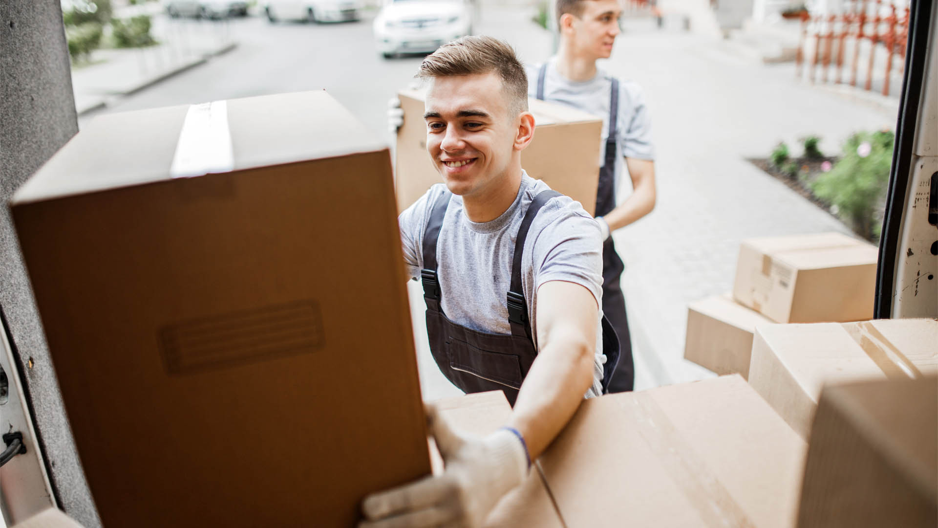 A young handsome smiling mover wearing uniform is reaching for t