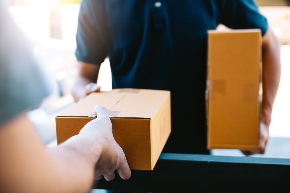 Close up of hands cargo staff are delivering cardboard boxes with parcels inside to the recipient's hand