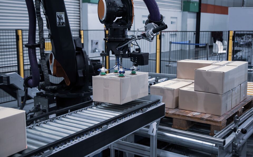 Industrial automated robot arm loading carton on conveyor