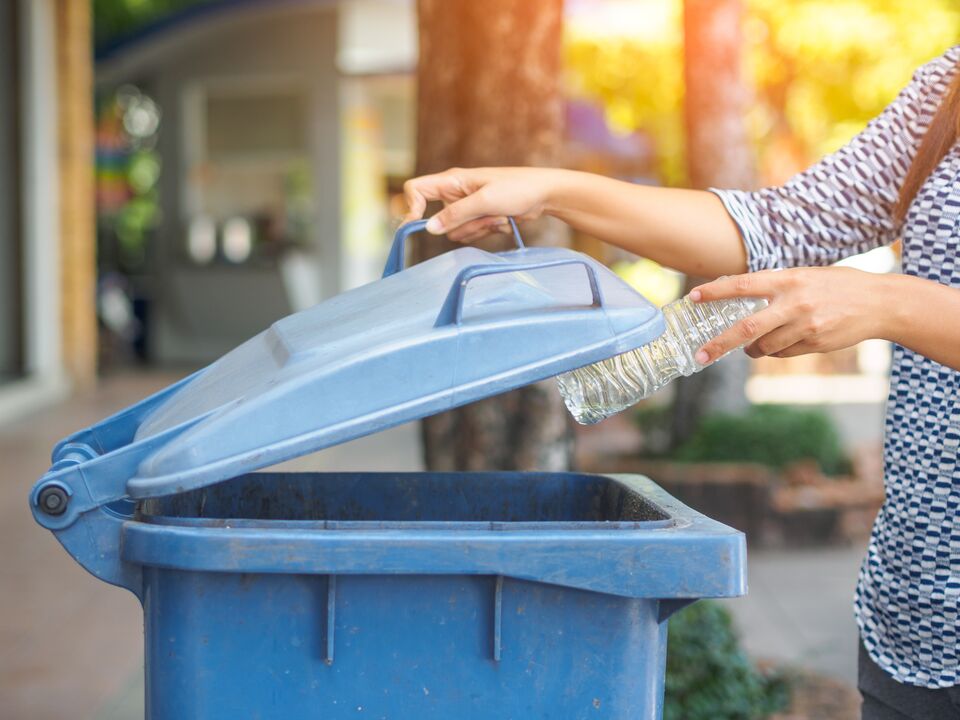 Closeup portrait woman hand throwing empty plastic water bottle in recycling bin