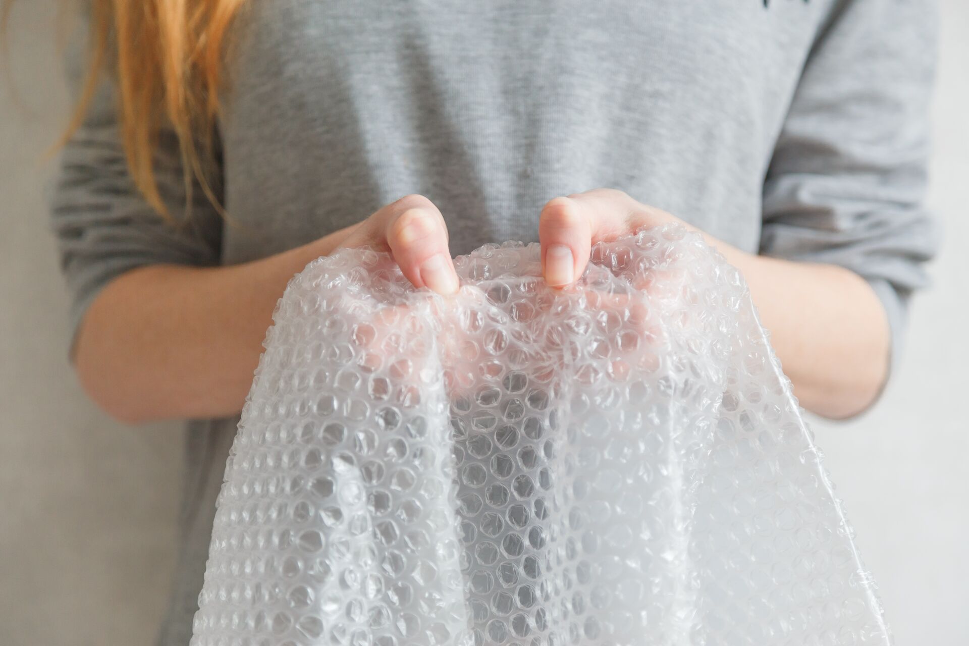 Female hands popping the bubbles in bubble wrap. Selective focus, close up