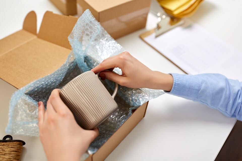 hands packing mug to parcel box at post office