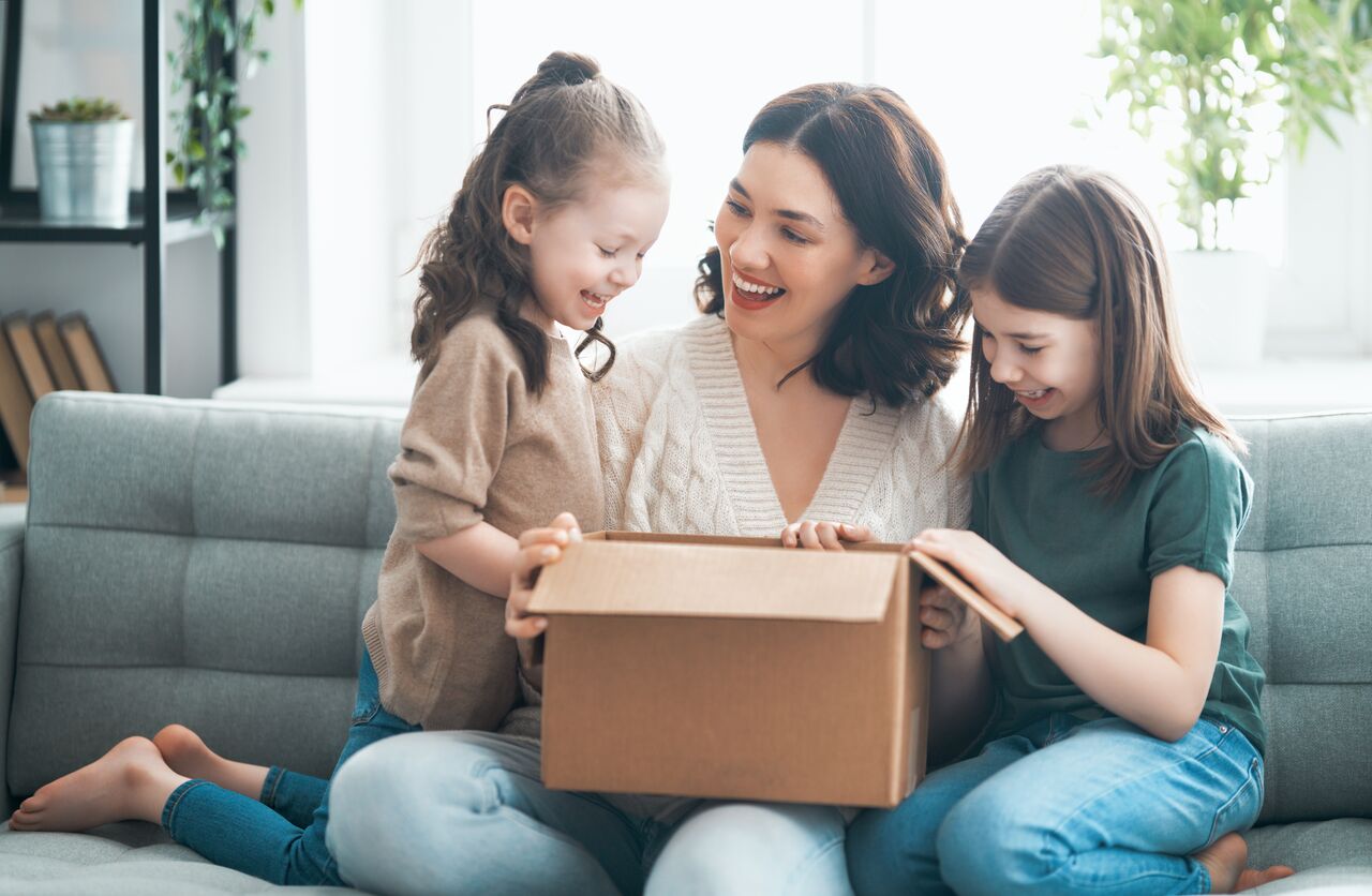 Mother and daughters are unpacking cardboard