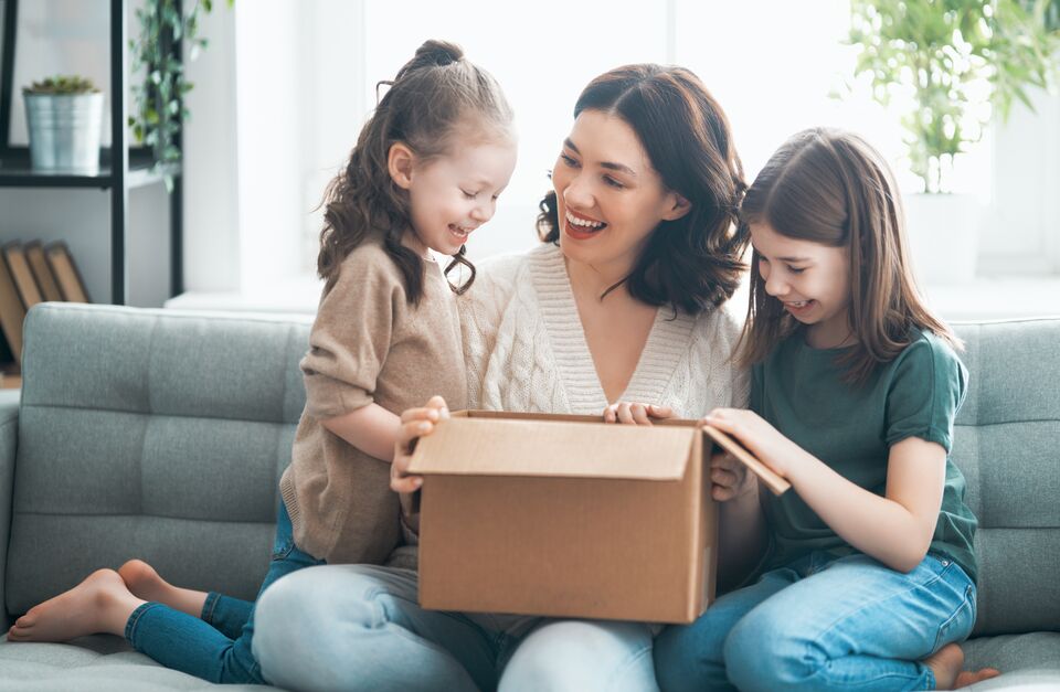Mother and daughters are unpacking cardboard