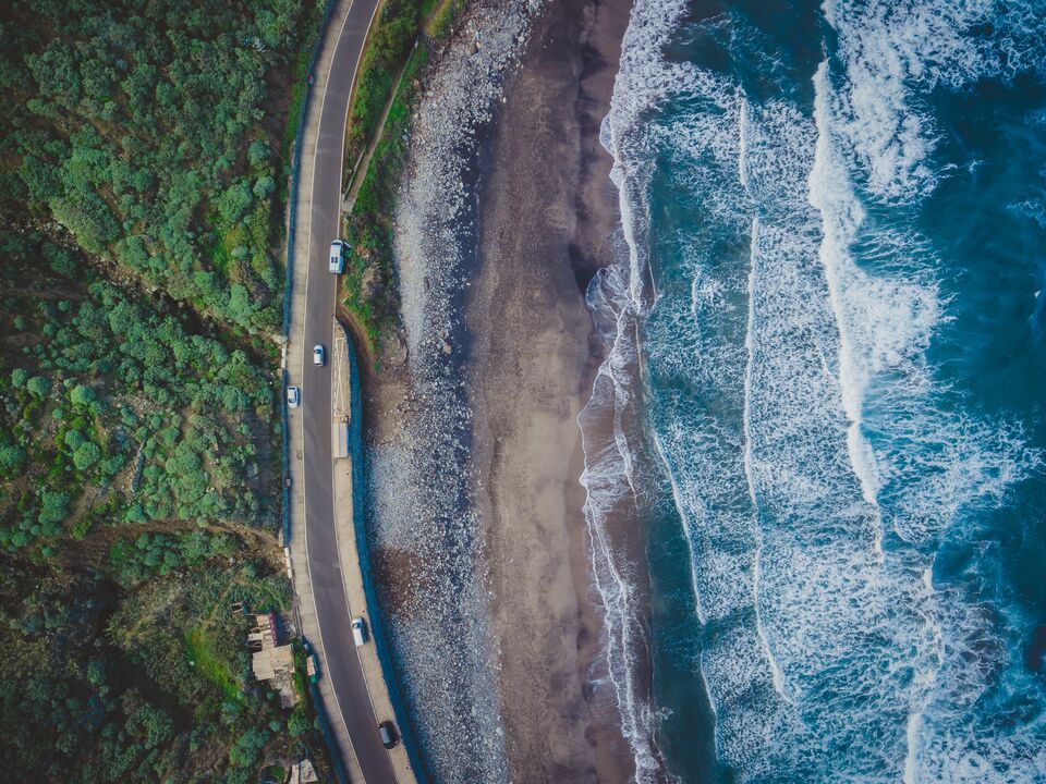 Volcanic sunset beach in Tenerife, Benijo. Paradise beach in Canary Island. Flight above ocean waves, washing up on a black volcanic sand beach. Aerial shot of tide, sea, wide dramatic landscape view